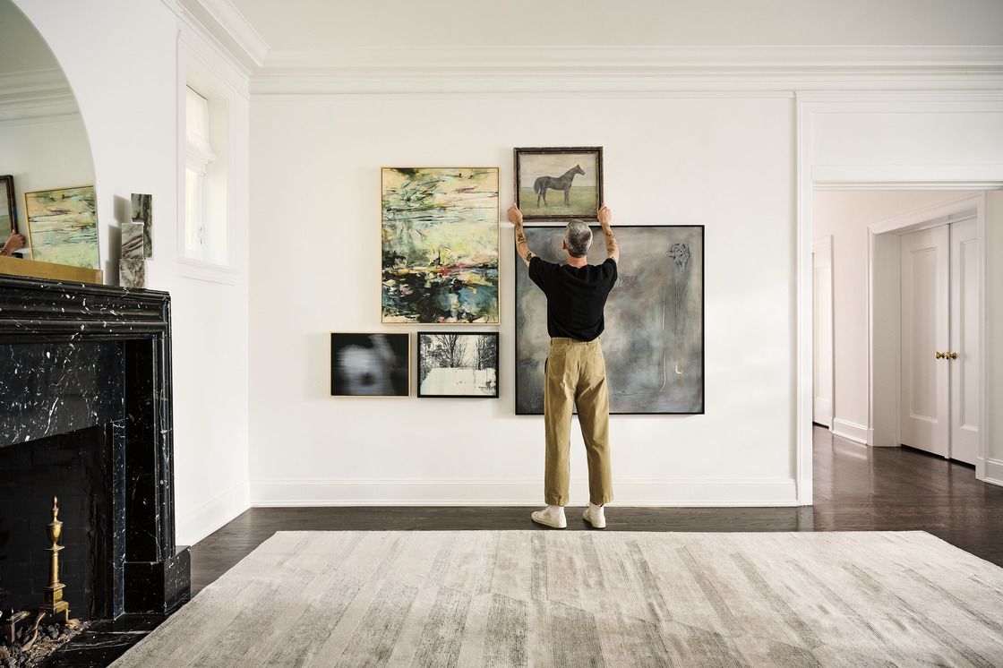 man hanging a gallery wall in his living room